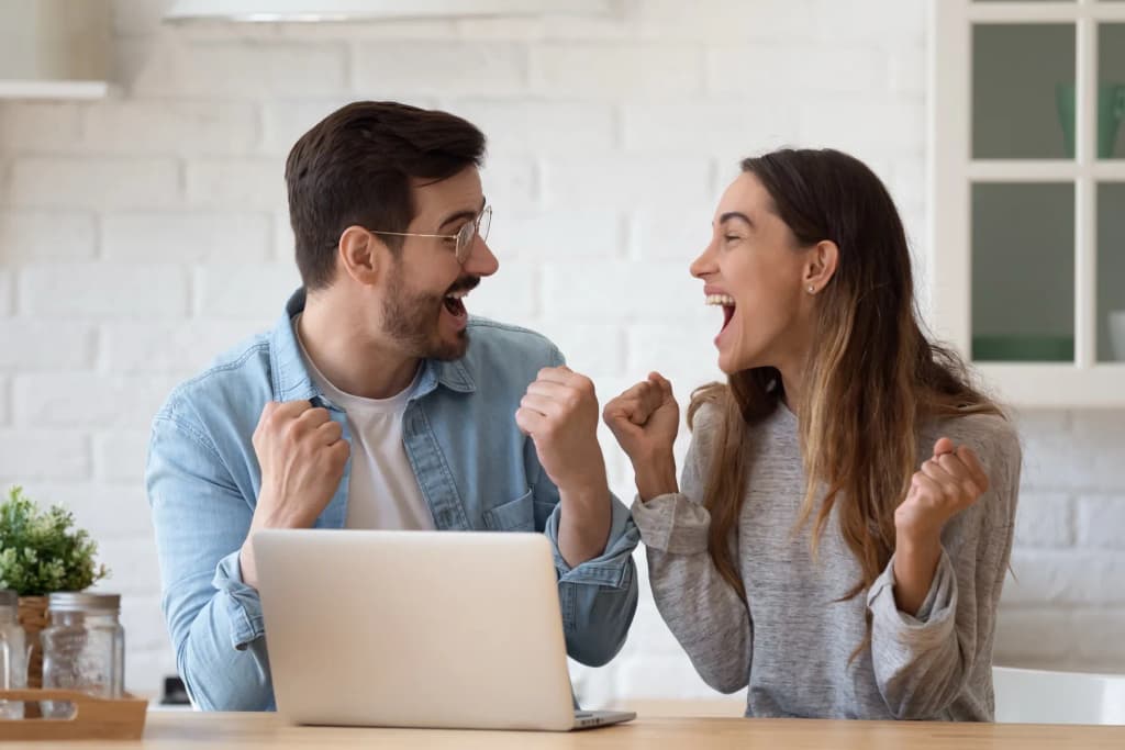 Un couple qui se réjouit devant un ordinateur